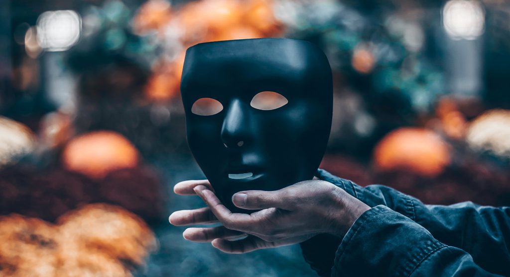 Hands holding a dark mask over colorful background