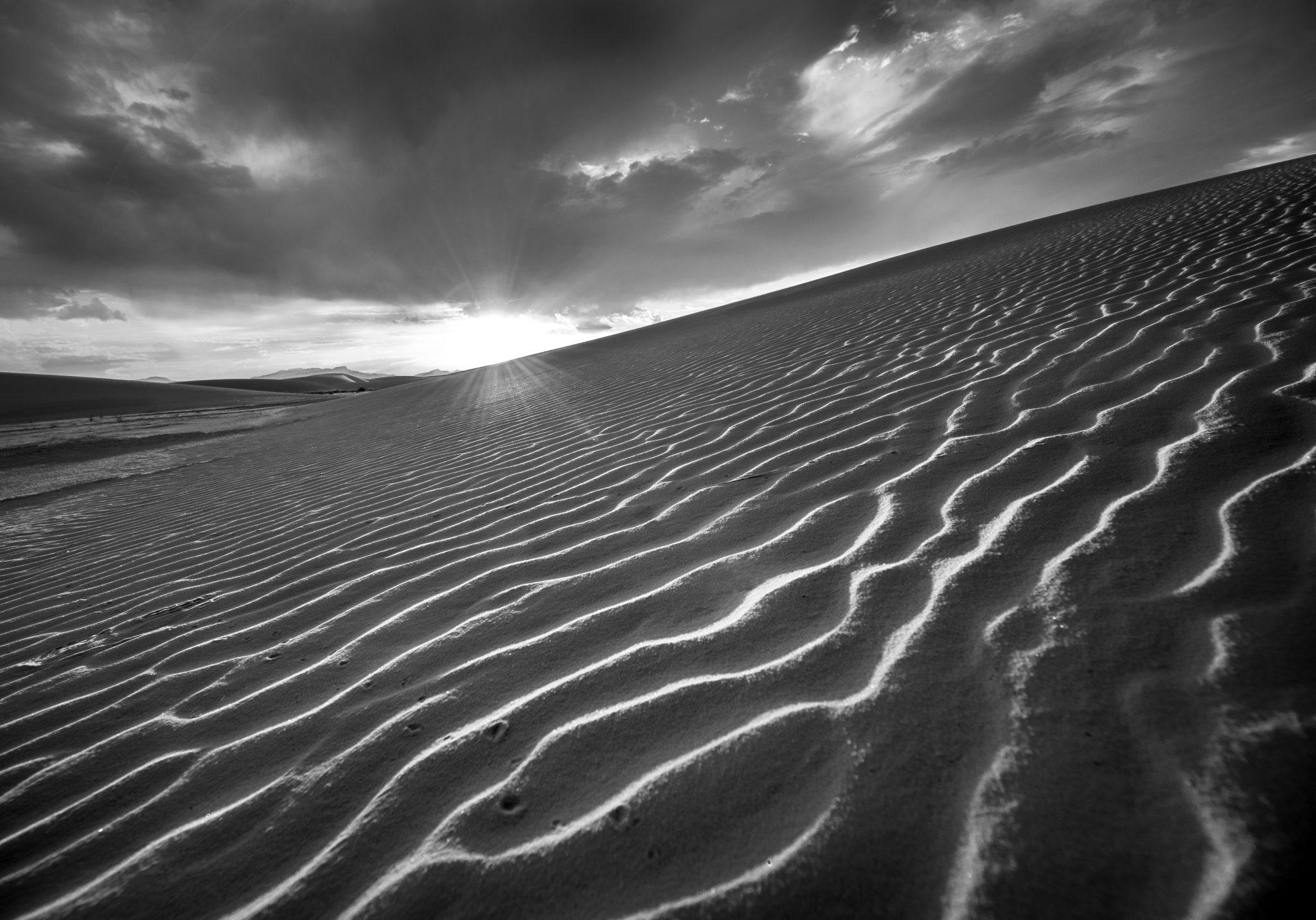 Black and white photo of a sand dune at dawn.