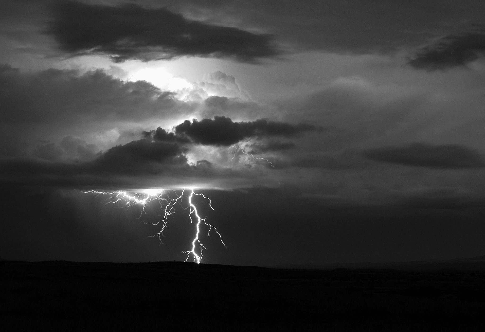 Black and white photo of a lightening bolt behind clouds